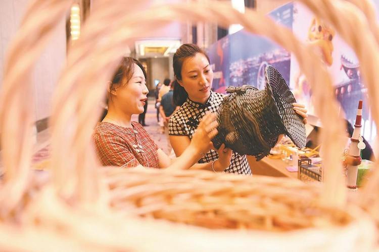 客商在阜阳市全域旅游推广月上观看"龙虎尊"柳编工艺品.
